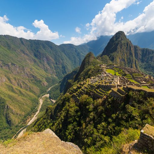 Machu Picchu archeological site illuminated by the sunlight. Wide angle view from the terraces above with scenic dramatic sky.